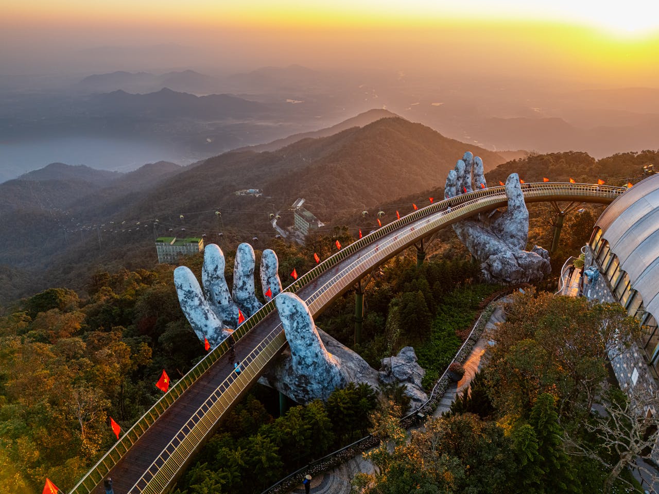 Aerial view of the iconic Hand Bridge in Ba Na Hills, Vietnam during a vibrant sunset.